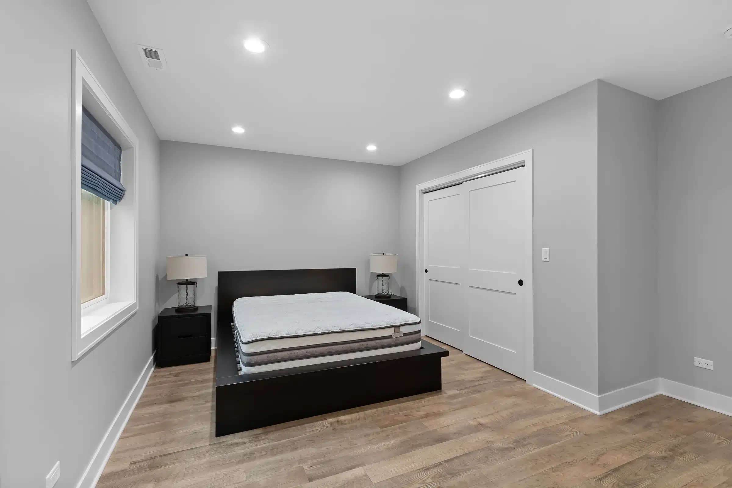 Modern basement guest bedroom in Palatine with large egress window, double closet doors, and luxury vinyl plank flooring.