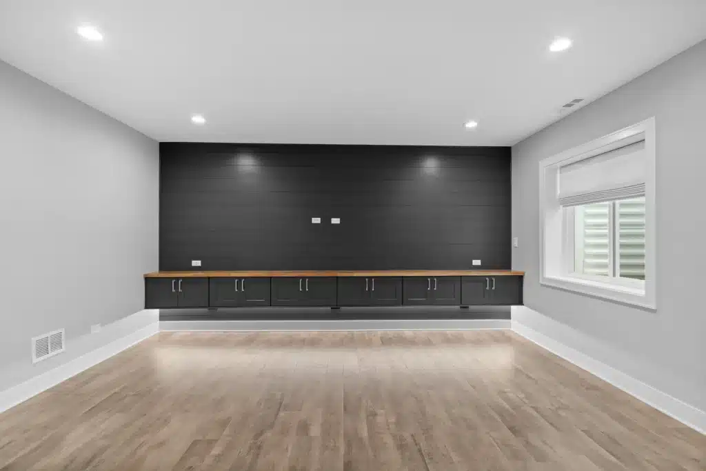 Custom basement entertainment wall featuring charcoal shiplap, floating black cabinets with a wood countertop, and LED accent lighting in Palatine.
