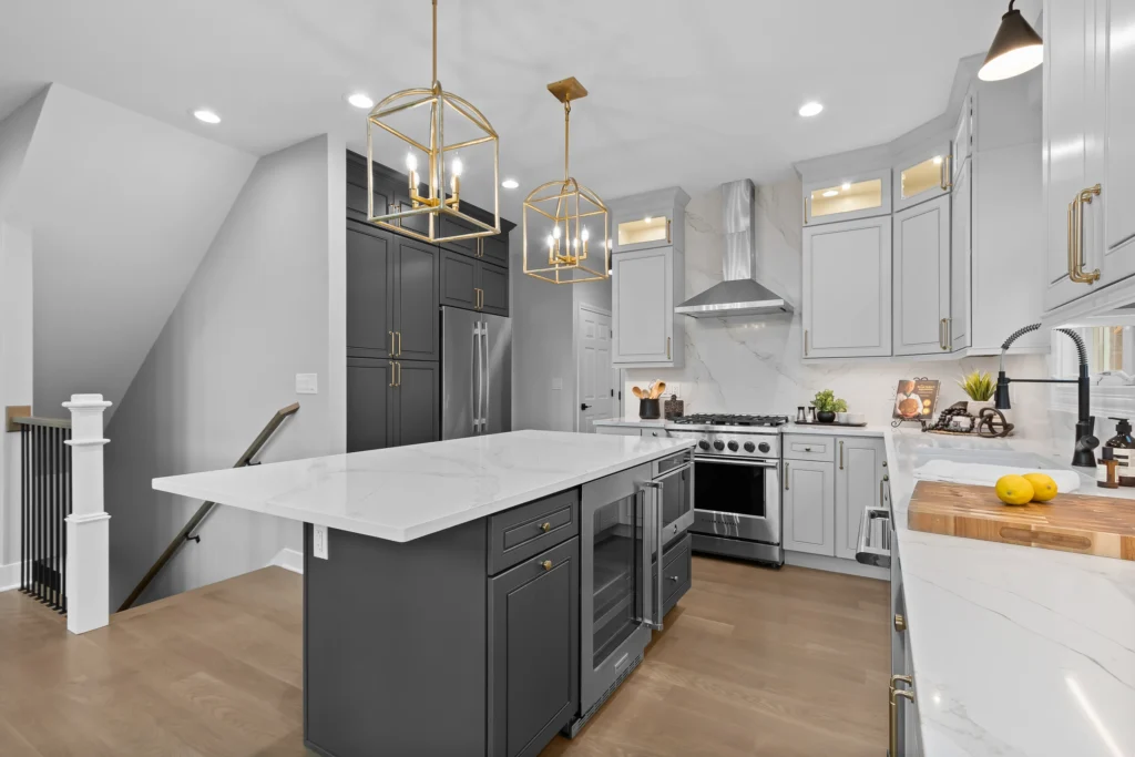 Modern kitchen renovation in Palatine featuring a charcoal grey island with a built-in wine fridge, white quartz countertops, and gold cage pendant lighting.