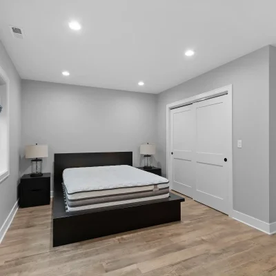 Modern basement guest bedroom in Palatine with large egress window, double closet doors, and luxury vinyl plank flooring.