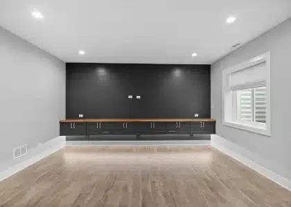 Modern basement media room with black shiplap accent wall, floating entertainment console, and luxury vinyl flooring in Palatine.