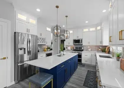 Transitional kitchen remodel in Palatine featuring white shaker cabinets, a navy blue island with quartz countertops, and brushed gold hardware.