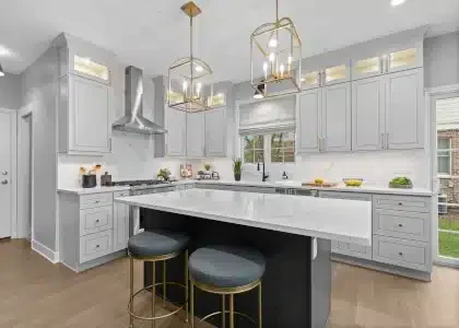 Luxury kitchen in Palatine featuring white quartz countertops with matching full-height quartz backsplash, gold cage pendant lights, and grey shaker cabinets.