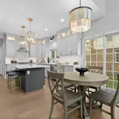 Open concept kitchen remodel in Palatine featuring white stacked cabinets, a charcoal gray island, gold pendant lighting, and an eat-in dining area.