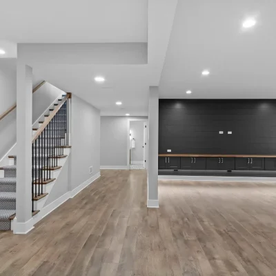 Finished basement layout in Palatine showing open staircase with carpet runner, luxury vinyl plank flooring, and a black shiplap entertainment wall.