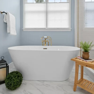 Freestanding white soaking tub with a floor-mounted brushed gold tub filler in a Palatine master bathroom with marble tile floors.