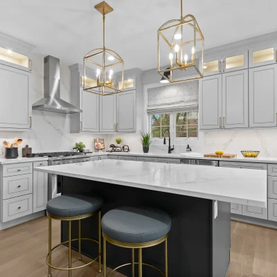 Modern kitchen renovation in Palatine featuring grey shaker style cabinets, glass-front upper cabinetry, gold cage pendant lights, and a full-height quartz backsplash.
