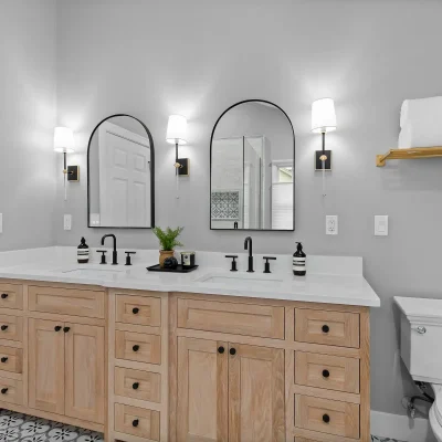 Modern bathroom renovation in Palatine featuring a natural light oak double vanity, matte black arched mirrors, and geometric floor tile.