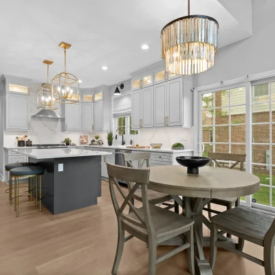 Modern eat-in kitchen in Palatine featuring a round grey wood dining table, a crystal drum chandelier, and large sliding glass patio doors leading to the backyard.