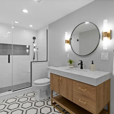 Modern bathroom remodel in Palatine featuring black and white geometric hexagon floor tiles, a natural wood vanity, and mixed black and gold fixtures.